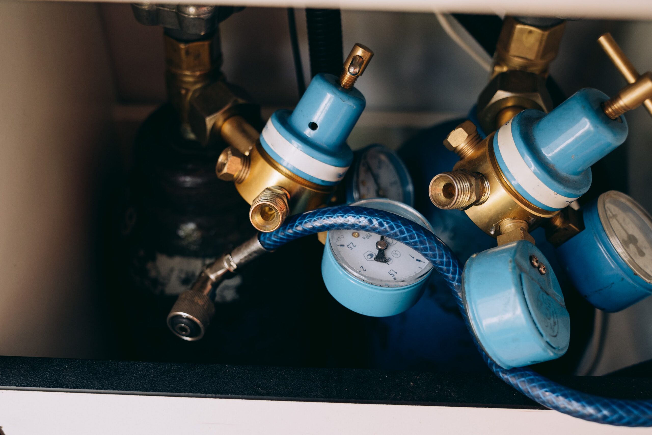 CO2 regulators and gauges beneath a bar, illustrating the beverage gas system this troubleshooting guide addresses.
