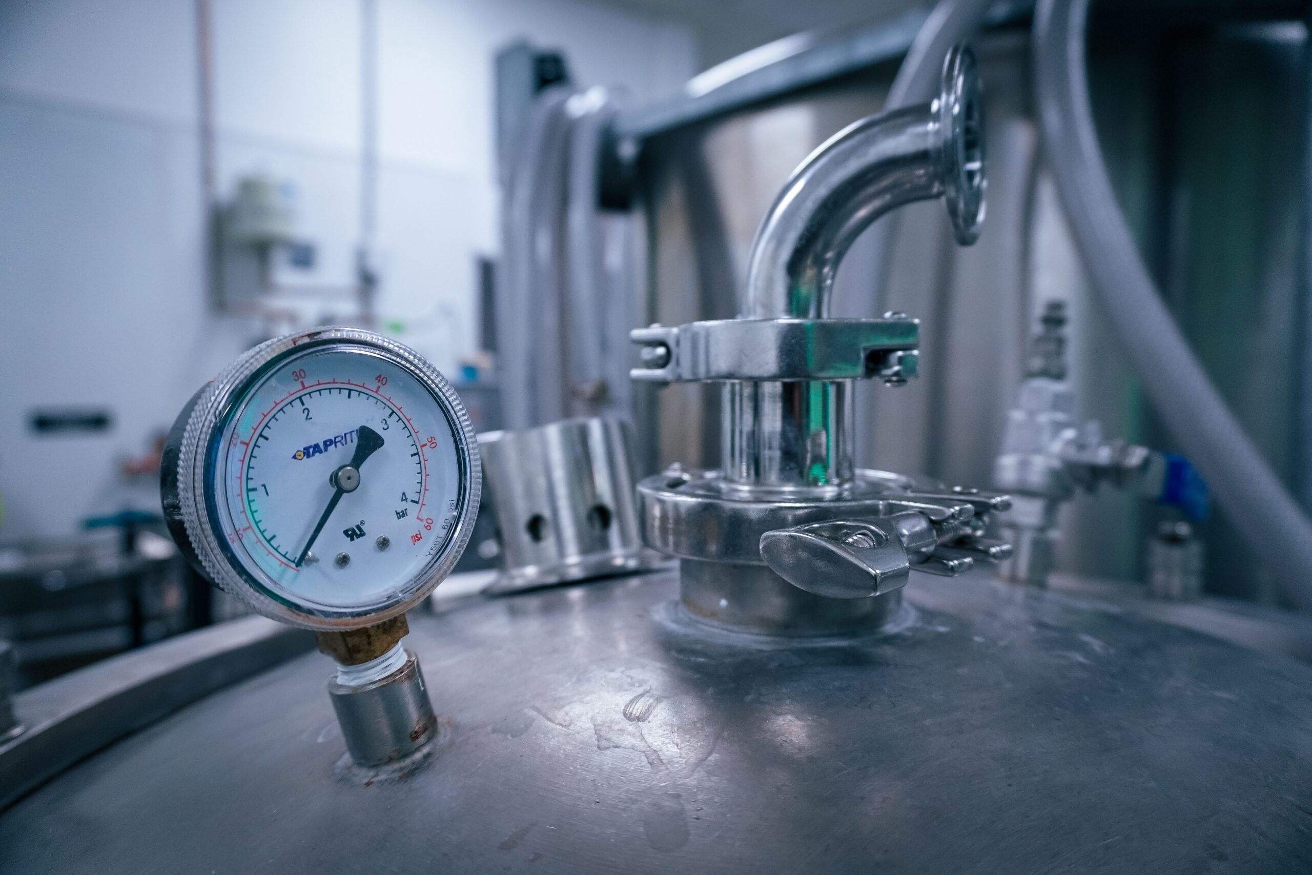 Close-up of a pressure gauge on a stainless steel keg coupler, showing the PSI readings that determine when a CO2 tank needs replacement or a system needs service.