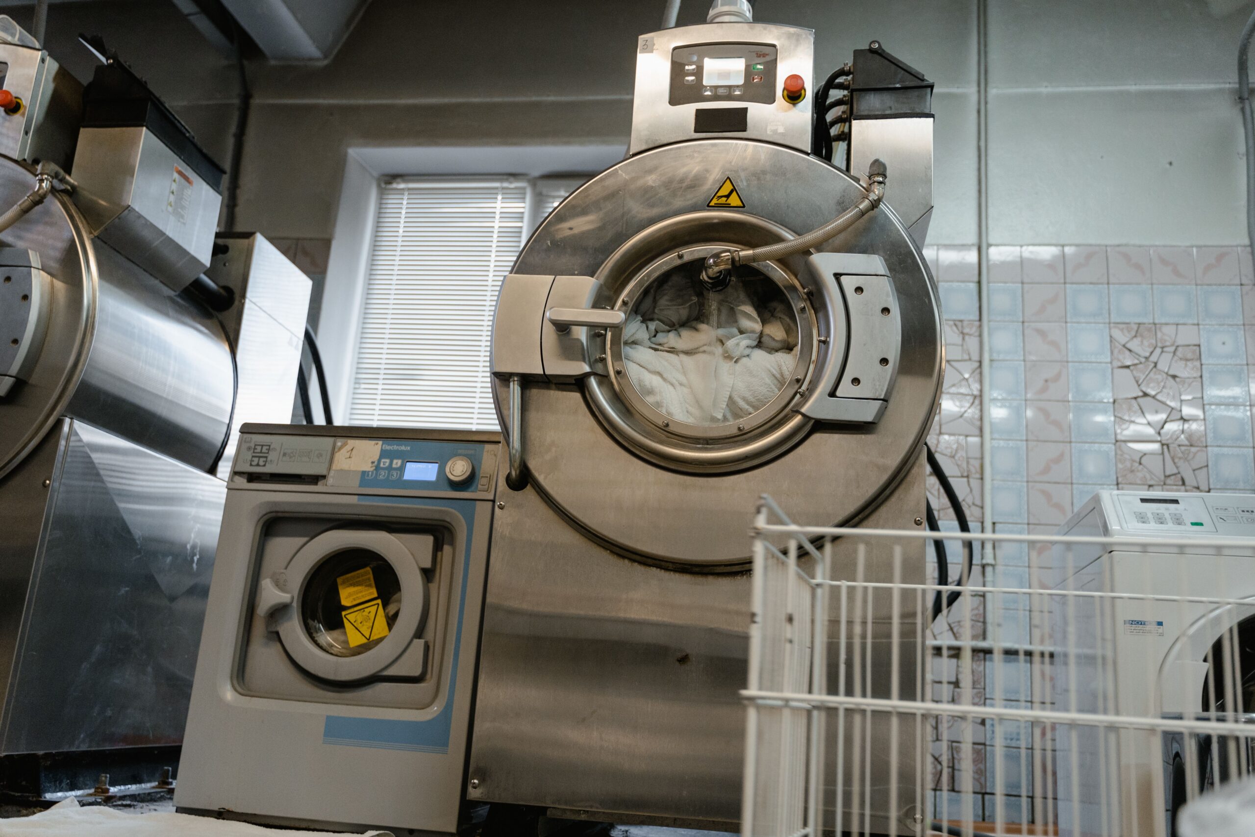 Open industrial washer-extractor loaded with white linens in a commercial laundry room