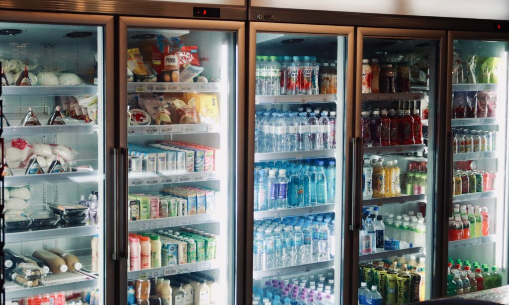 Row of glass-door coolers stocked with bottled drinks, snacks and fresh food in a micro market
