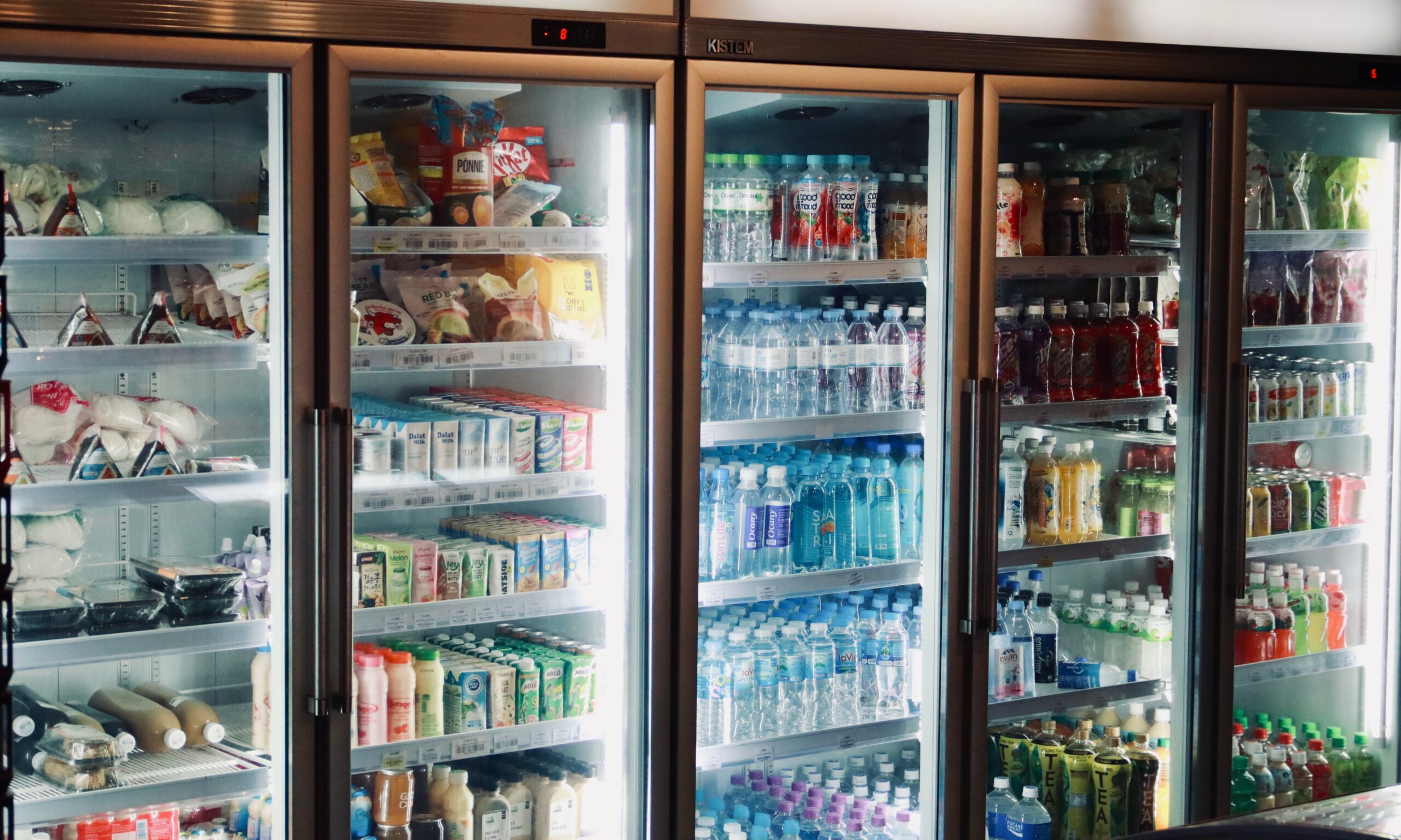 Row of glass-door coolers stocked with bottled drinks, snacks and fresh food in a micro market