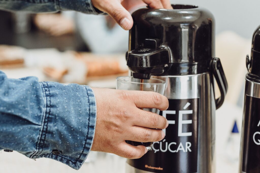 Coffee being poured from a commercial airpot dispenser, the kind of brewing equipment supplied through a hotel coffee program.