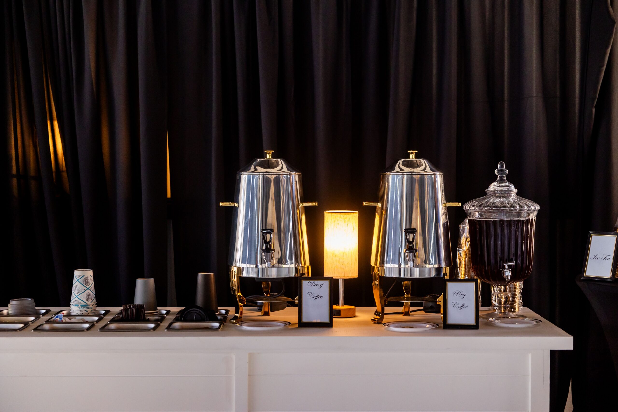 Self-serve hotel coffee station with commercial dispensers for regular and decaf coffee, cups, and beverage supplies.