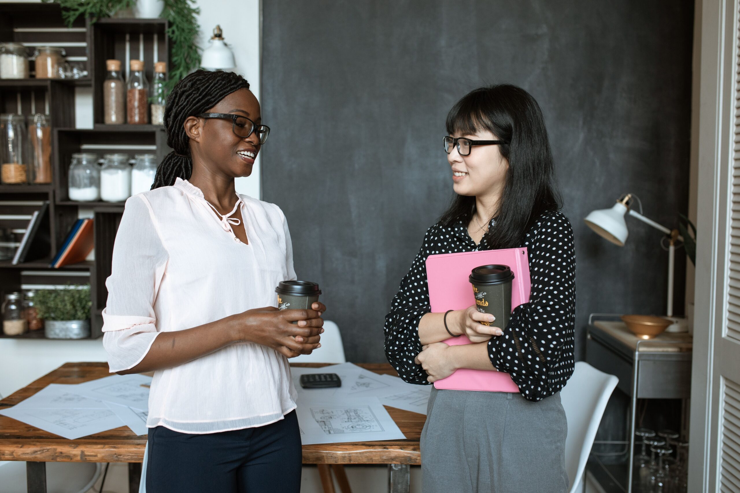 Coworkers chatting with coffee in an office setting, reflecting the role refreshment programs play in workplace culture.