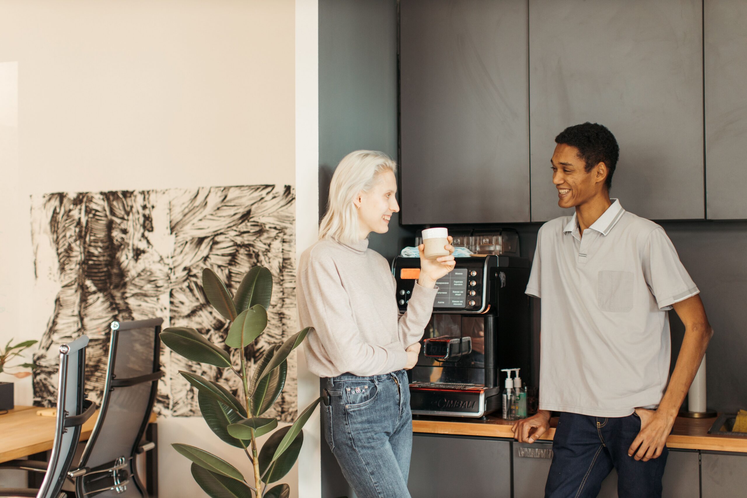 Coworkers chatting over coffee in an office breakroom.
